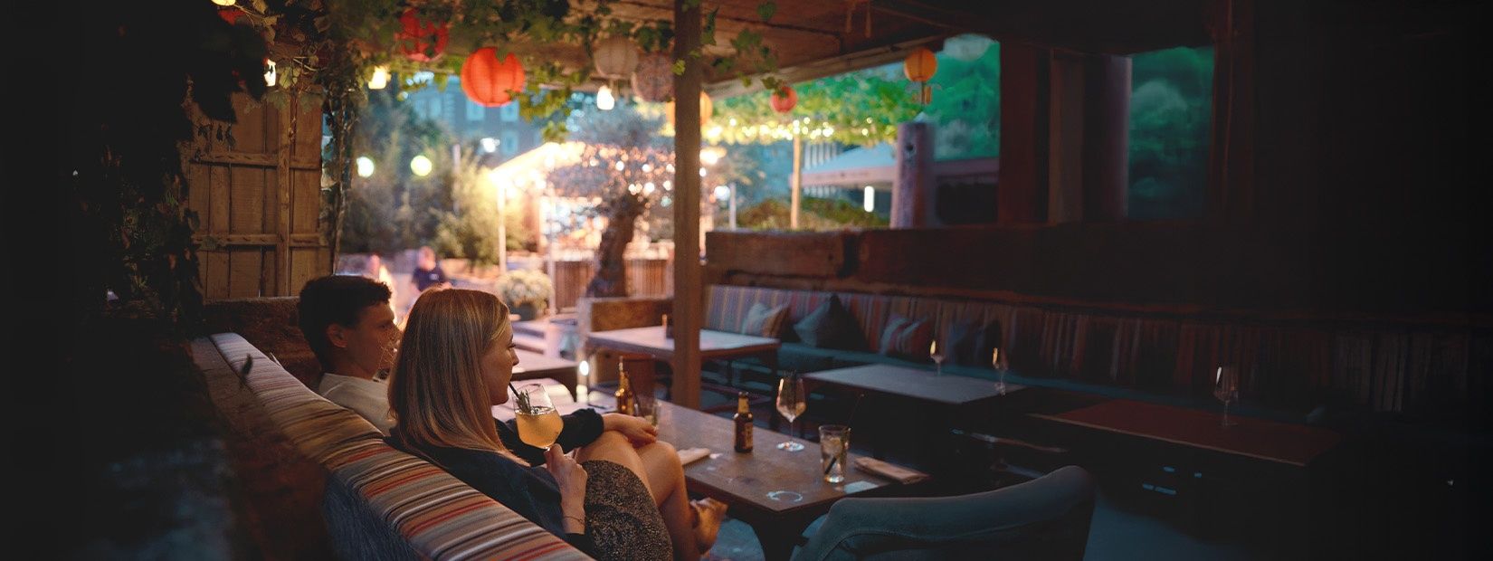 Fröhliche Gäste genießen im Liebesbier Gastrogarten Bier und Cocktails.